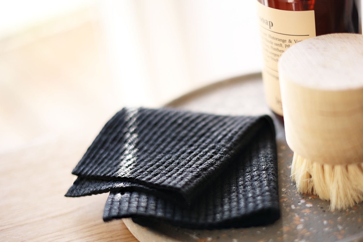 Spültücher Schwarz waschbar auf einem Tablett mit Seife und Bürste.